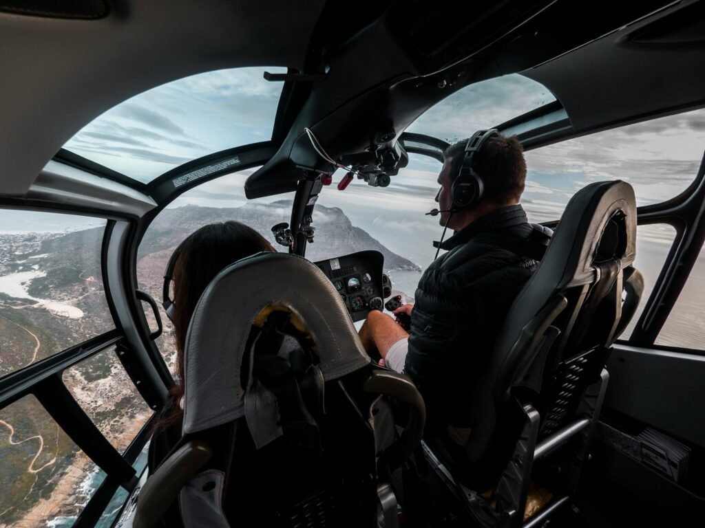 A photo of a two people in a helicopter flying over the savannah in kenya